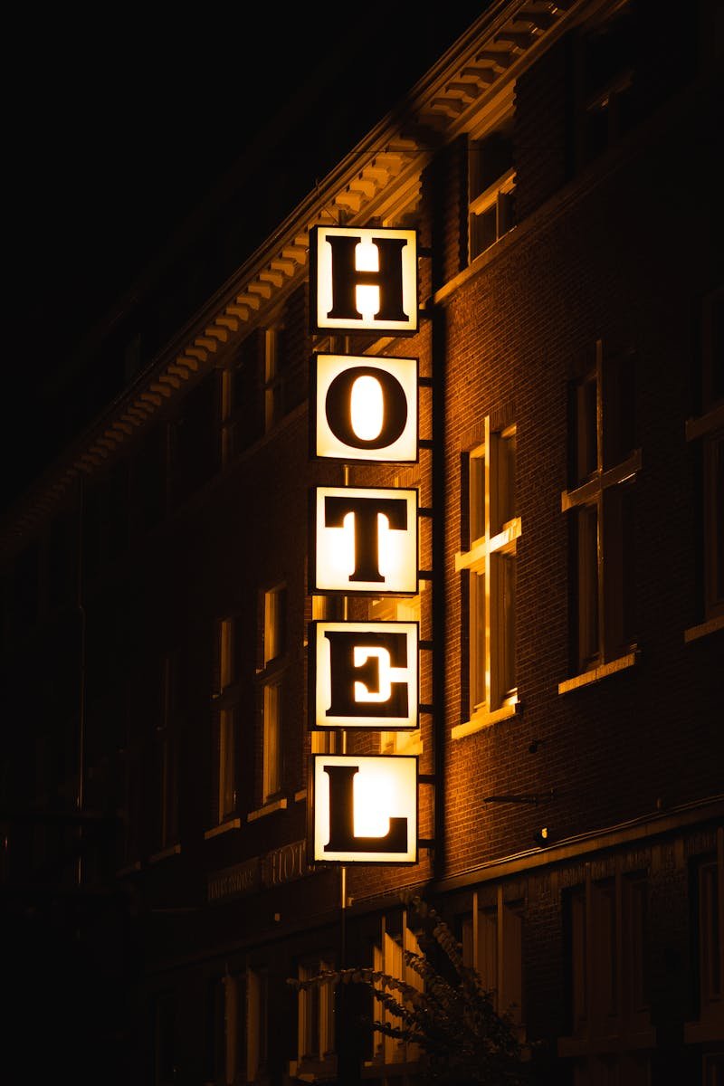 A bright hotel sign glowing on a building facade during nighttime.